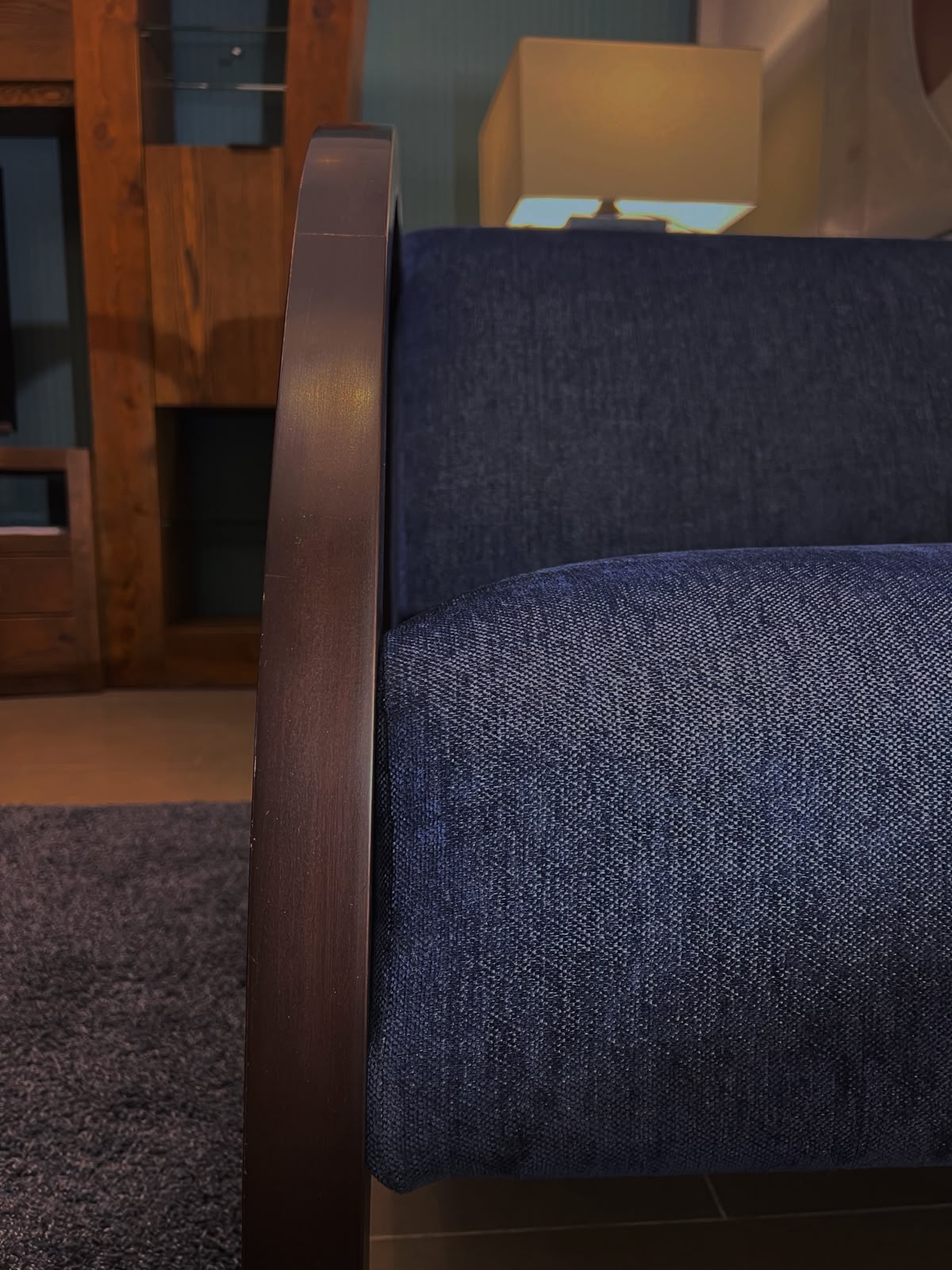 Primer plano de la madera raulí y la textura del tapiz azul de la poltrona – El Ciprés