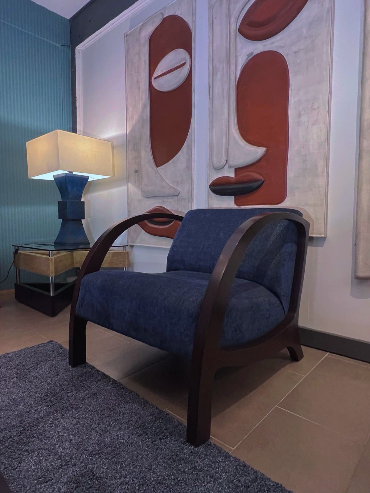 Poltrona orgánica de raulí con tapiz azul, ambientada en living junto a una lámpara – El Ciprés